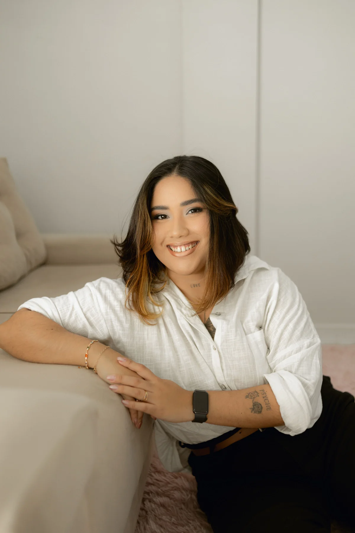 Lydhia Lins sorrindo ao lado do sofá do consultório